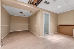 Finished room featuring wood-finish flooring, drop ceiling with recessed lighting, and neutral wall paint with wainscoting - 