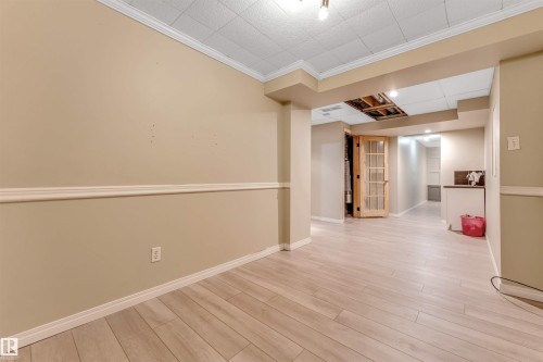 Lower level featuring wood-finish flooring, neutral wall tones, decorative chair rail molding, and a grid pattern drop ceiling - 135 150 Edwards Drive, Edmonton, AB - Indoor