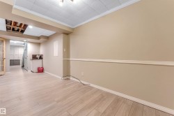 Spacious room featuring wood-finish flooring, neutral-toned walls with chair rail molding, and a drop ceiling - 