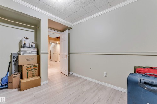 Room featuring wood-finish flooring, light-toned walls with chair rail molding, and crown molding - 135 150 Edwards Drive, Edmonton, AB - Indoor