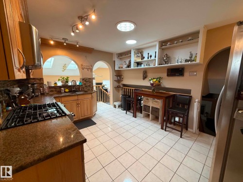 Kitchen featuring wood cabinetry, granite countertops, and a tiled backsplash - 2812 35 Street, Edmonton, AB - Indoor