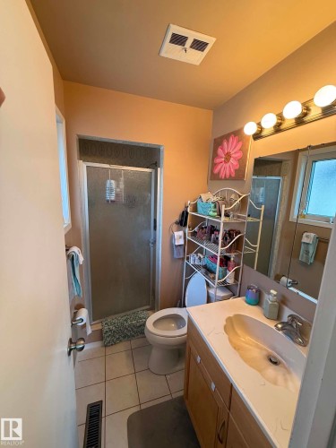Full bathroom featuring a shower enclosure with a frosted glass door, a toilet, and a vanity with a built-in sink and wood-finish cabinetry - 2812 35 Street, Edmonton, AB - Indoor Photo Showing Bathroom