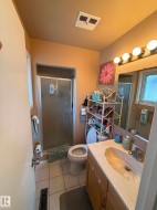 Full bathroom featuring a shower enclosure with a frosted glass door, a toilet, and a vanity with a built-in sink and wood-finish cabinetry - 