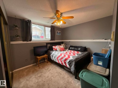 Carpeted room featuring a ceiling fan with light fixture, a window with white trim, and a white baseboard - 2812 35 Street, Edmonton, AB - Indoor Photo Showing Bedroom