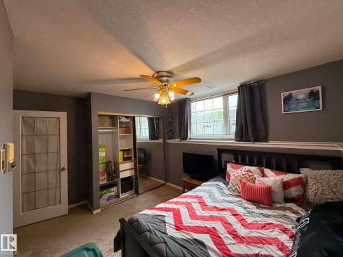 Carpeted interior space featuring a ceiling fan with integrated lighting, a mirrored sliding closet door, and a white framed window with a lower sill - 2812 35 Street, Edmonton, AB - Indoor Photo Showing Bedroom