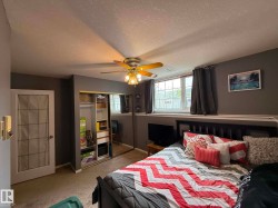 Carpeted interior space featuring a ceiling fan with integrated lighting, a mirrored sliding closet door, and a white framed window with a lower sill - 