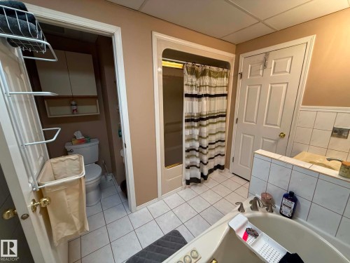 Bathroom featuring a soaking tub with tile surround, a shower enclosure with a clear glass door, and a separate water closet with built-in cabinetry - 2812 35 Street, Edmonton, AB - Indoor Photo Showing Bathroom