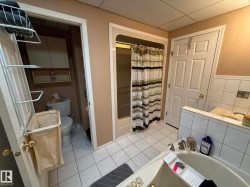 Bathroom featuring a soaking tub with tile surround, a shower enclosure with a clear glass door, and a separate water closet with built-in cabinetry - 
