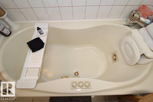 Cream-toned jetted tub featuring integrated controls and a tile surround - 2812 35 Street, Edmonton, AB - Indoor Photo Showing Bathroom