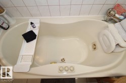 Cream-toned jetted tub featuring integrated controls and a tile surround - 