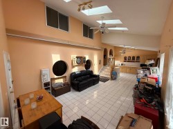 Spacious open-concept interior featuring tiled flooring, multiple skylights, and ceiling fans - 