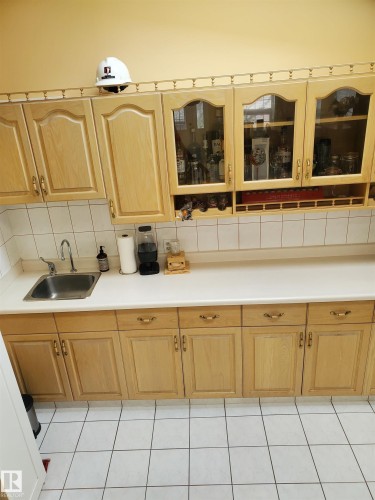 Light wood-finish cabinetry with glass-front upper cabinets and integrated wine storage - 2812 35 Street, Edmonton, AB - Indoor Photo Showing Kitchen