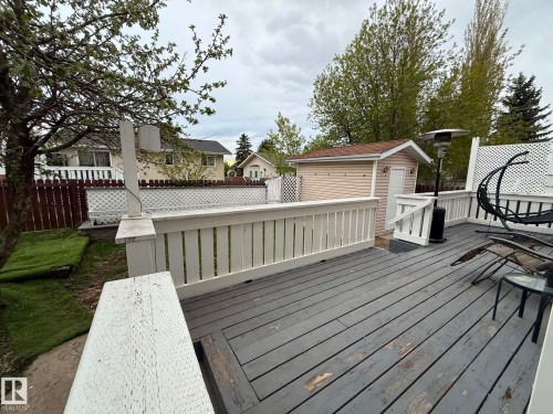 Expansive wooden deck with white railing, featuring a detached storage shed with vinyl siding and an asphalt shingle roof - 2812 35 Street, Edmonton, AB - Outdoor With Deck Patio Veranda With Exterior