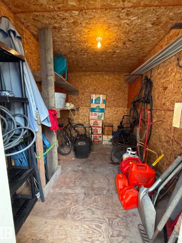 Utility structure interior featuring OSB wall and ceiling panels, plywood flooring, an exposed light fixture, and a built-in wooden shelf - 2812 35 Street, Edmonton, AB - Indoor
