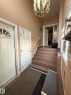 Foyer featuring a contemporary chandelier, tile flooring, two paneled entry doors, a staircase with a white handrail, and a window providing natural light - 2812 35 Street, Edmonton, AB  - Indoor Photo Showing Other Room 