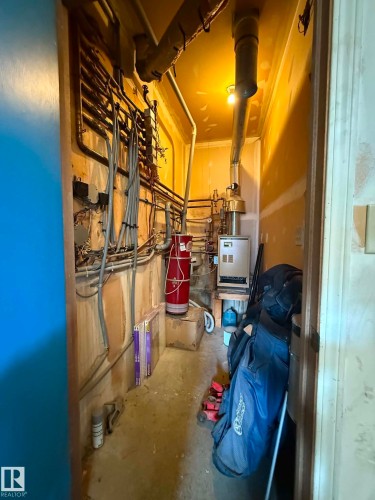 Utility closet featuring exposed piping, a red water heater, and a wall-mounted boiler system - 2812 35 Street, Edmonton, AB - Indoor