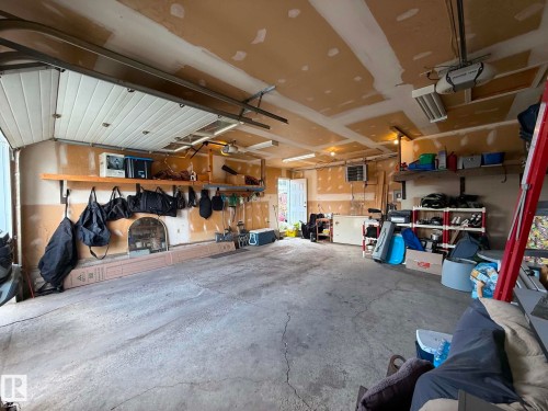 Spacious garage featuring a concrete floor, overhead garage door, built-in shelving, track lighting, and a utility door - 2812 35 Street, Edmonton, AB - Indoor Photo Showing Garage
