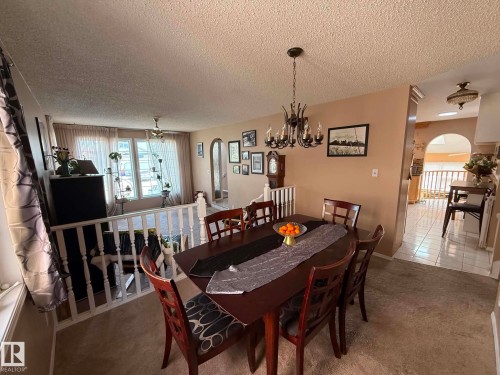 Dining area featuring a chandelier, carpet flooring, and a wall archway - 2812 35 Street, Edmonton, AB - Indoor Photo Showing Dining Room