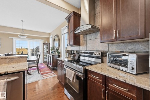 Kitchen featuring granite countertops, dark wood cabinetry, and stainless steel appliances - 1590 Chapman Way, Edmonton, AB 