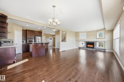 Spacious room featuring wood-finish flooring, a stone-surround fireplace with a white mantel, and multiple windows - 