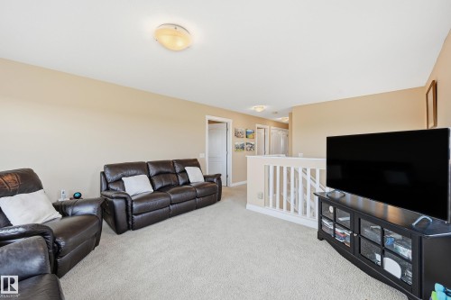 Carpeted upper-level space featuring neutral-toned walls and a white spindle railing - 1590 Chapman Way, Edmonton, AB 
