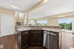 Kitchen island featuring a built-in stainless steel sink, dishwasher, dark wood cabinetry, and granite countertops - 