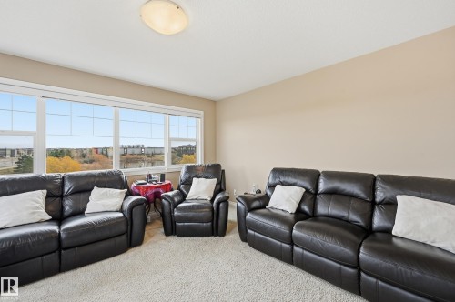Room featuring a wall of windows, neutral wall tones, and carpeted flooring - 1590 Chapman Way, Edmonton, AB 
