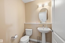Pedestal sink with chrome faucet, complemented by an oval mirror and a two-light vanity fixture - 