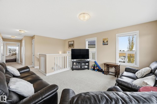 Carpeted open area with light beige walls and white trim - 1590 Chapman Way, Edmonton, AB 