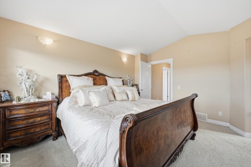 Carpeted room featuring sconce lighting, vaulted ceilings, and a doorway leading to an additional space - 1590 Chapman Way, Edmonton, AB 