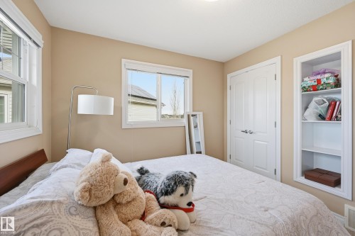 Bright room featuring two large windows with white trim, a built-in shelving unit, and a double-door closet with white paneled doors - 1590 Chapman Way, Edmonton, AB 