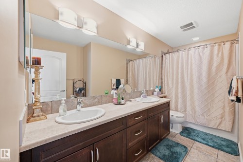 Double vanity featuring dark wood-finish cabinetry, light-toned countertops, and dual undermount sinks - 1590 Chapman Way, Edmonton, AB 