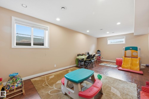 Spacious room featuring rich wood-finish flooring, recessed lighting, and a large window with white trim - 1590 Chapman Way, Edmonton, AB 