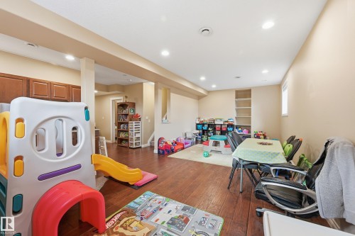 Finished basement featuring wood-finish flooring, recessed lighting, built-in shelving, and a cabinet system with upper and lower storage - 1590 Chapman Way, Edmonton, AB 