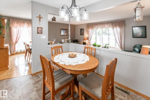 Dining area featuring a central chandelier, wood-finish flooring, and a window with exterior views - 4611 Lakeshore Drive, Bonnyville Town, AB - Indoor Photo Showing Dining Room