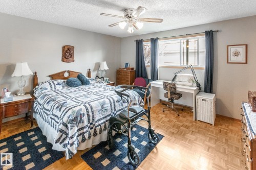 Room featuring wood-finish parquet flooring, a ceiling fan with integrated lighting, and multiple windows with trim - 4611 Lakeshore Drive, Bonnyville Town, AB - Indoor Photo Showing Bedroom