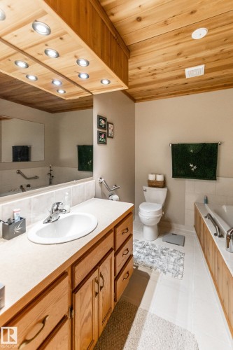 Bathroom vanity with an integrated sink, wood cabinetry, and a full-width mirror - 4611 Lakeshore Drive, Bonnyville Town, AB - Indoor Photo Showing Bathroom