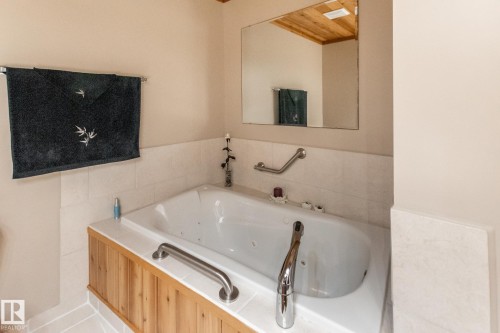 Soaking tub featuring wood-finish paneling, white tile surround, and chrome fixtures - 4611 Lakeshore Drive, Bonnyville Town, AB - Indoor Photo Showing Bathroom
