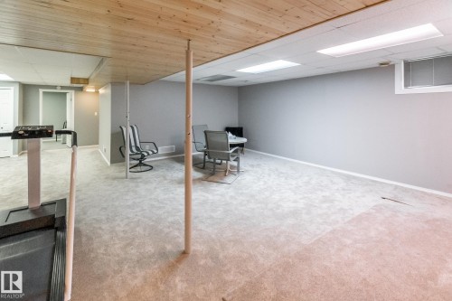 Finished lower level featuring a light wood-paneled ceiling, recessed lighting, neutral gray walls, light gray carpeting, and a window with horizontal blinds - 4611 Lakeshore Drive, Bonnyville Town, AB - Indoor Photo Showing Basement