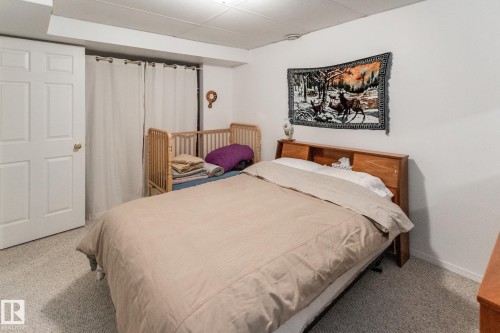 Carpeted room with a paneled white door and a wooden bed frame featuring a built-in headboard - 4611 Lakeshore Drive, Bonnyville Town, AB - Indoor Photo Showing Bedroom