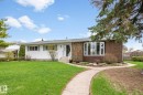 Exterior featuring a white siding facade, a brick-clad section with a bay window, a concrete pathway, and a mature front lawn - 4611 Lakeshore Drive, Bonnyville Town, AB  - Outdoor 