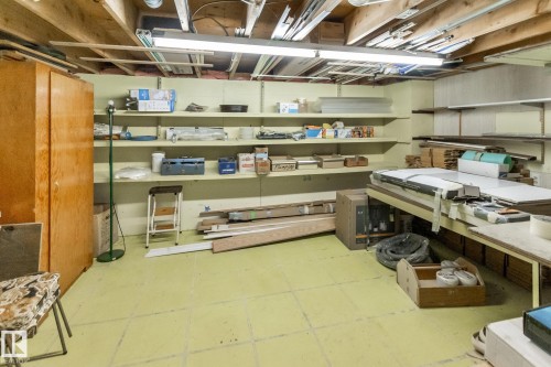 Utility space with exposed ceiling joists, fluorescent lighting, built-in shelving, a wooden storage cabinet, and a tiled floor - 4611 Lakeshore Drive, Bonnyville Town, AB - Indoor Photo Showing Basement