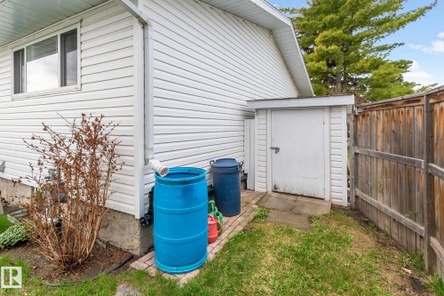 White vinyl siding exterior with an integrated storage shed and a wood fence - 4611 Lakeshore Drive, Bonnyville Town, AB - Outdoor With Exterior