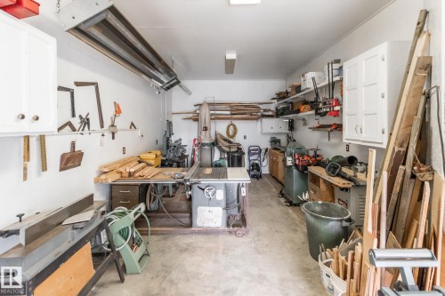 Spacious garage featuring a concrete floor, overhead lighting, wall-mounted cabinetry, and open shelving for organized storage - 4611 Lakeshore Drive, Bonnyville Town, AB - Indoor
