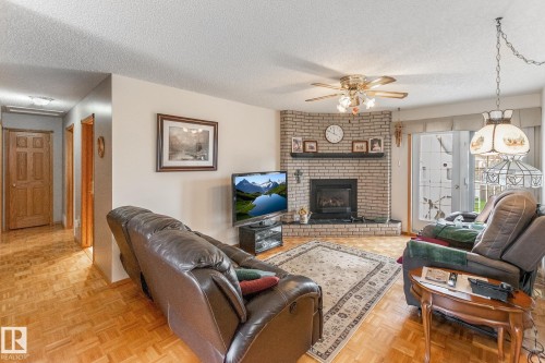 Living area featuring light wood-finish flooring and a brick fireplace with a dark hearth - 4611 Lakeshore Drive, Bonnyville Town, AB - Indoor Photo Showing Living Room With Fireplace