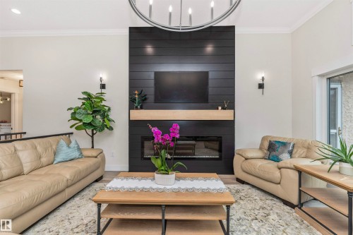 Living room featuring a contemporary black shiplap fireplace surround with a light wood mantle, a built-in electric fireplace, and light wood-finish flooring - 627 Forest Lane, Edmonton, AB - Indoor Photo Showing Living Room With Fireplace
