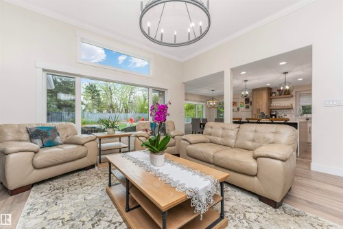 Living area featuring a vaulted ceiling with crown molding, a contemporary chandelier, and wood-finish flooring - 627 Forest Lane, Edmonton, AB - Indoor Photo Showing Living Room