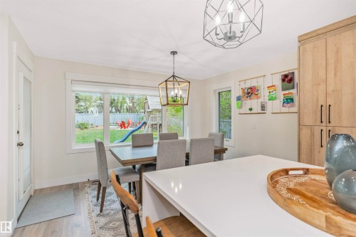 Dining area with wood-finish flooring, a contemporary chandelier, and a large window overlooking the backyard - 627 Forest Lane, Edmonton, AB - Indoor Photo Showing Dining Room