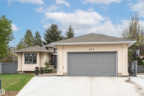 Exterior featuring a stucco finish, attached garage with a panel door, and a concrete driveway - 627 Forest Lane, Edmonton, AB - Outdoor