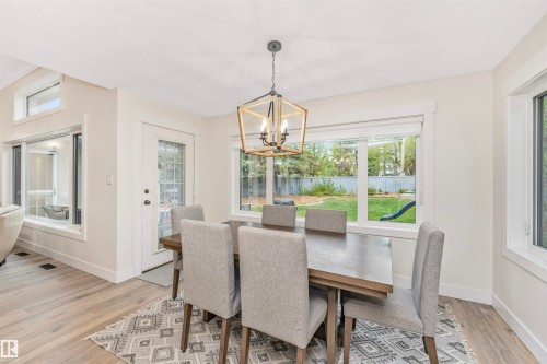 Dining area featuring light wood-finish flooring, a geometric chandelier, and multiple windows - 627 Forest Lane, Edmonton, AB - Indoor Photo Showing Dining Room
